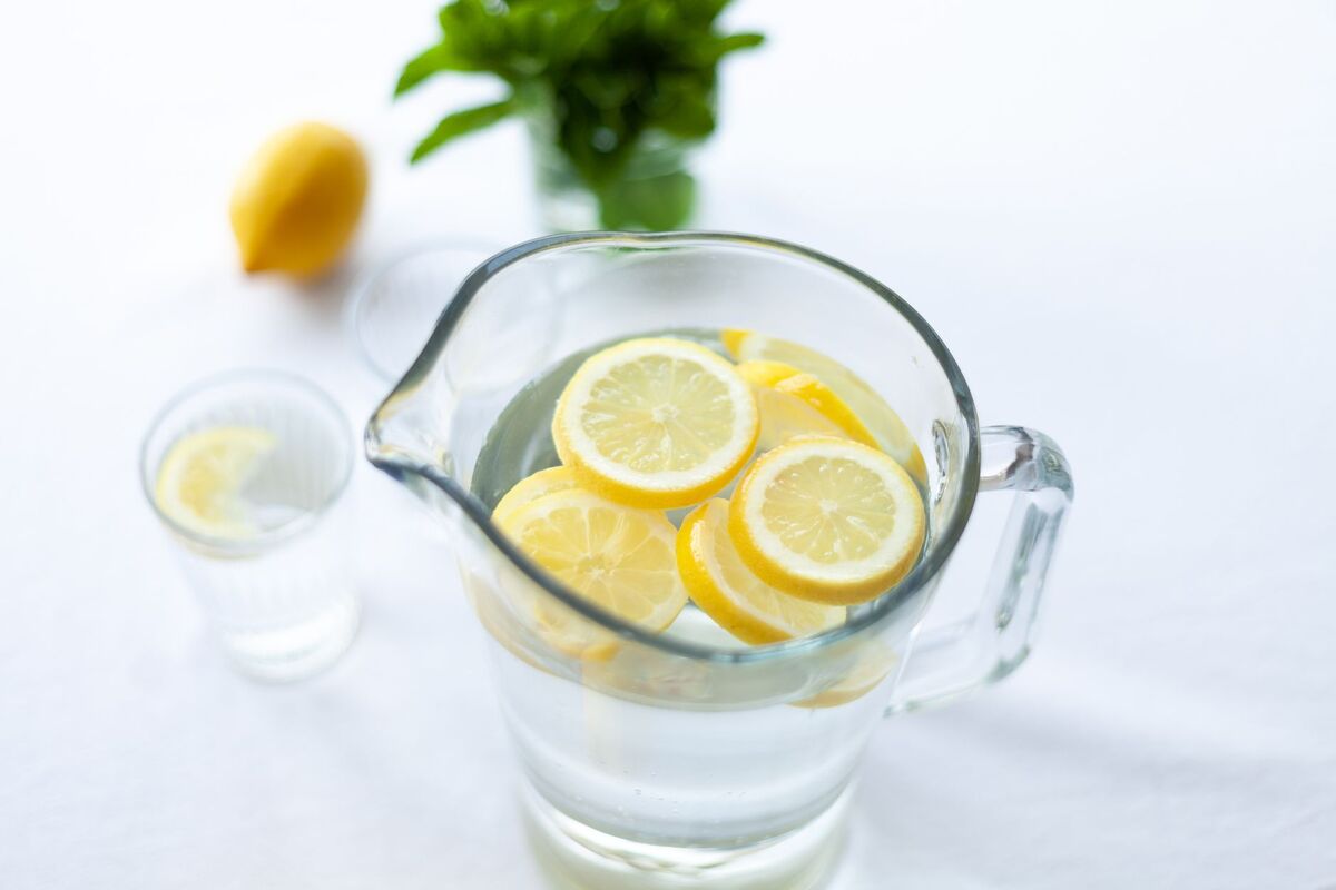 Carafe d’eau avec des rondelles de citron sur une table claire
