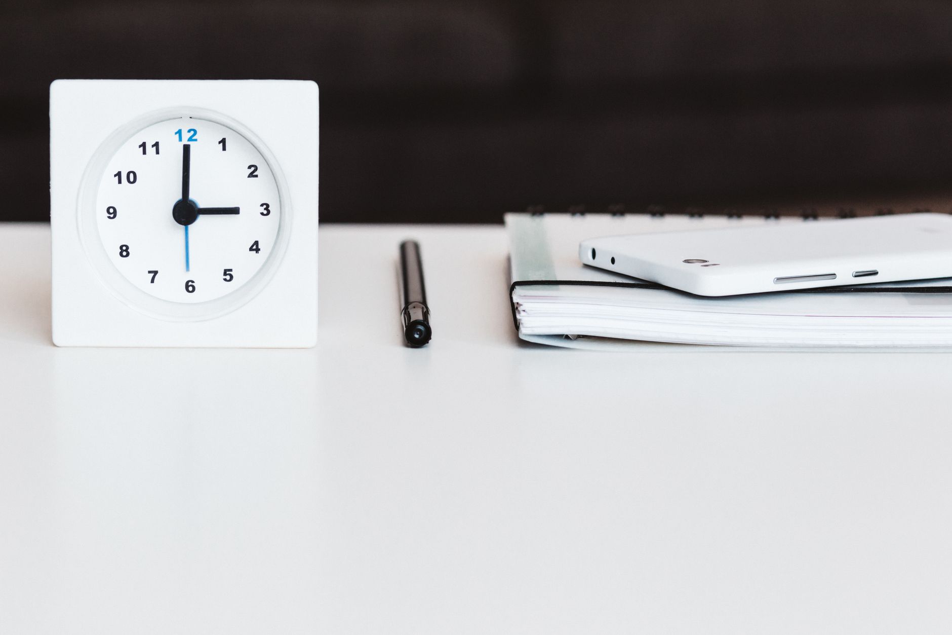 Horloge posée sur un bureau avec un carnet et un téléphone