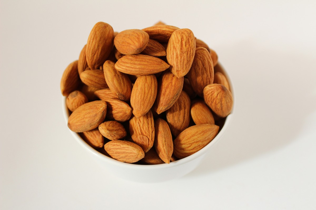 Amandes entières décortiquées dans une coupelle blanche posée sur une table