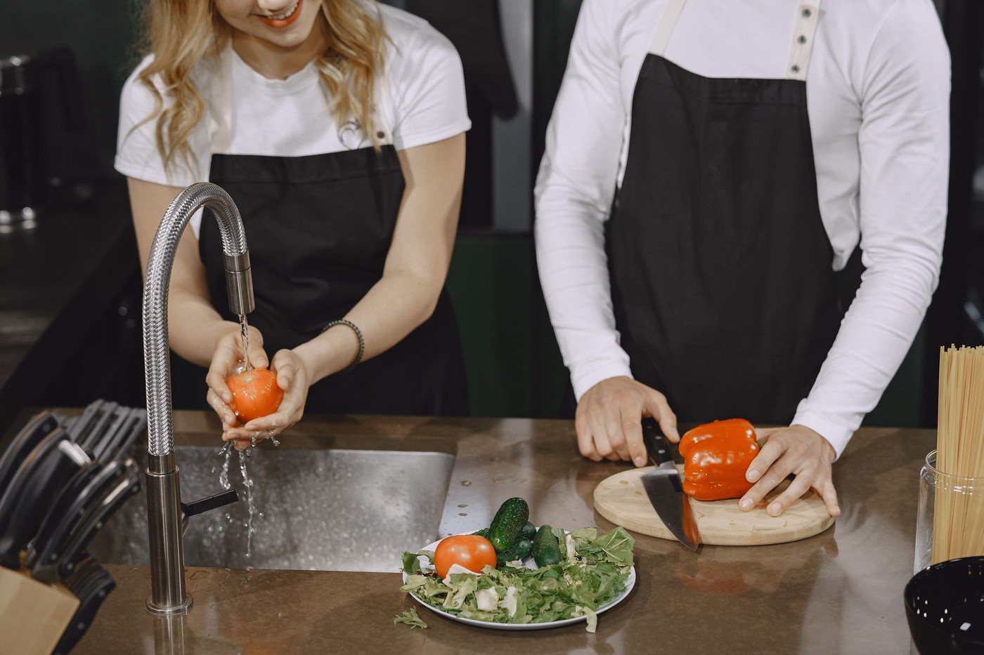 Nettoyage des légumes sous l'eau courante et découpe sur plan de travail en cuisine